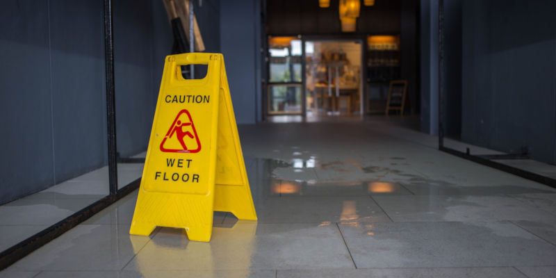 a 'caution wet floor' sign in front of a liquid spill on the floor